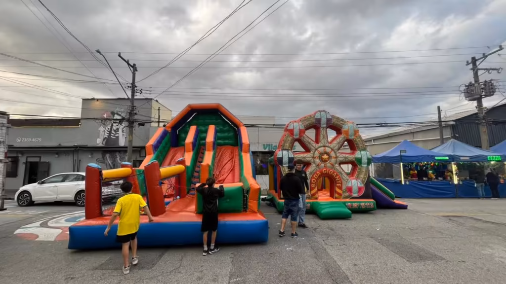 Crianças brincando em inflável multiatividades durante festa em quintal na zona leste